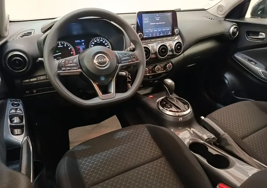 Intérieur du Nissan Juke 2023, vue avant centrée sur le volant multifonctions et la console avec écran tactile.