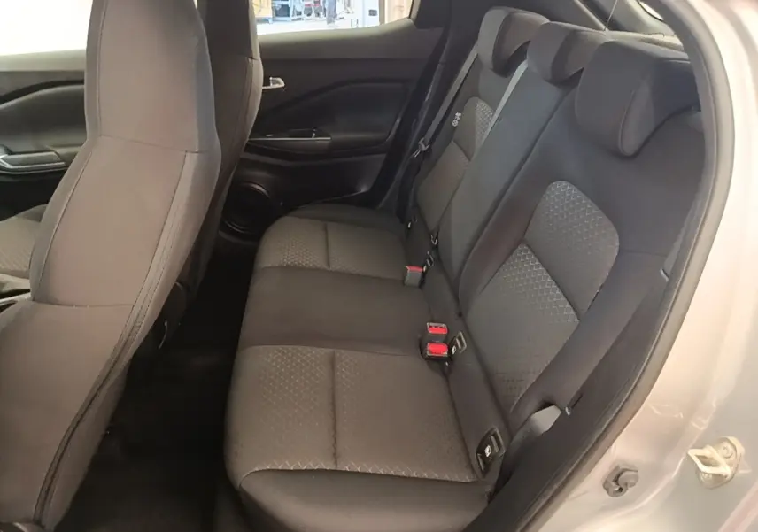 Vue intérieure côté droit sur la banquette arrière noire du Nissan Juke gris clair 2023, avec ceintures et appuie-têtes visibles.