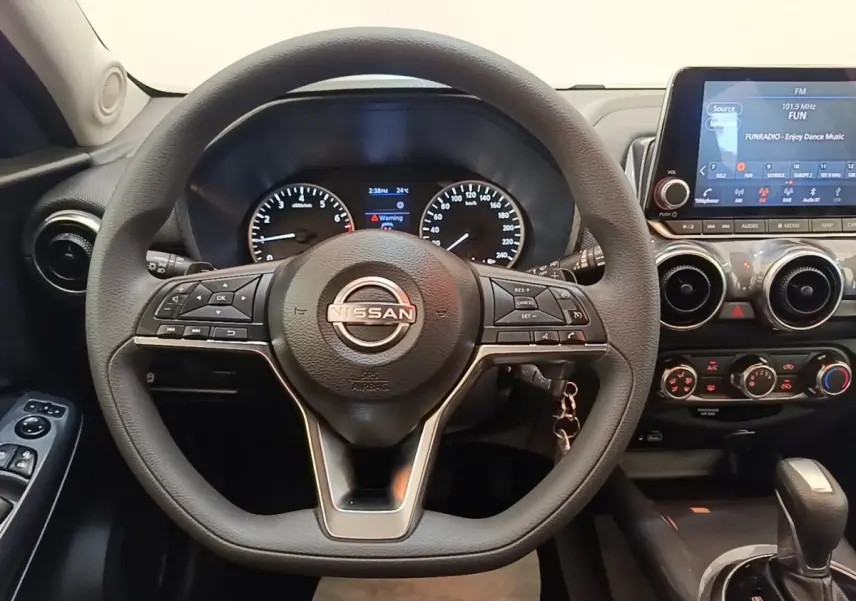 Vue intérieure centrée sur le volant noir du Nissan Juke 2023 avec tableau de bord et écran tactile visible à droite.