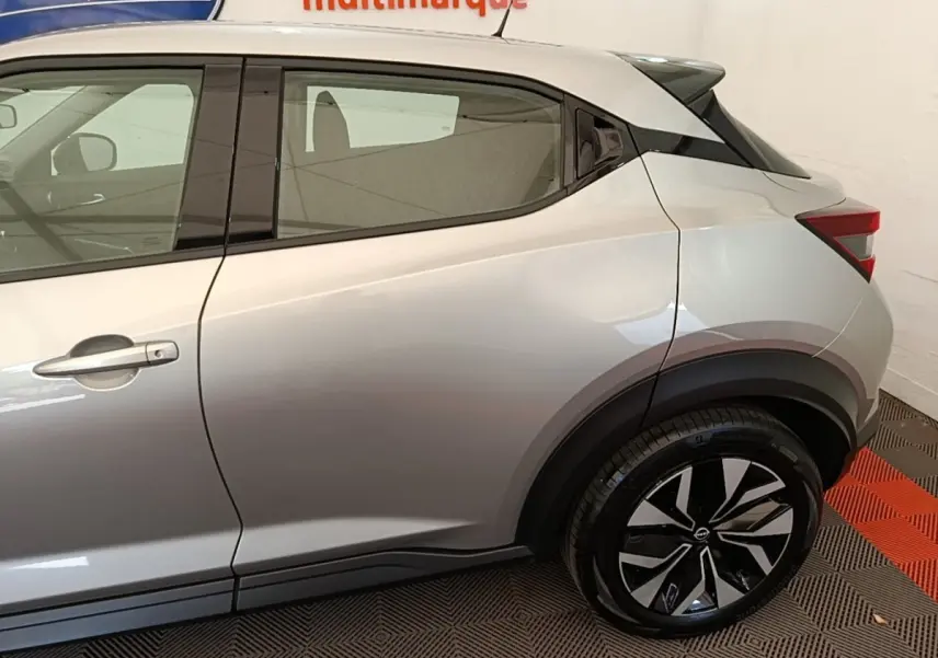 Vue latérale côté gauche du Nissan Juke gris clair 2023 avec jantes alliage et poignées de porte ton caisse.