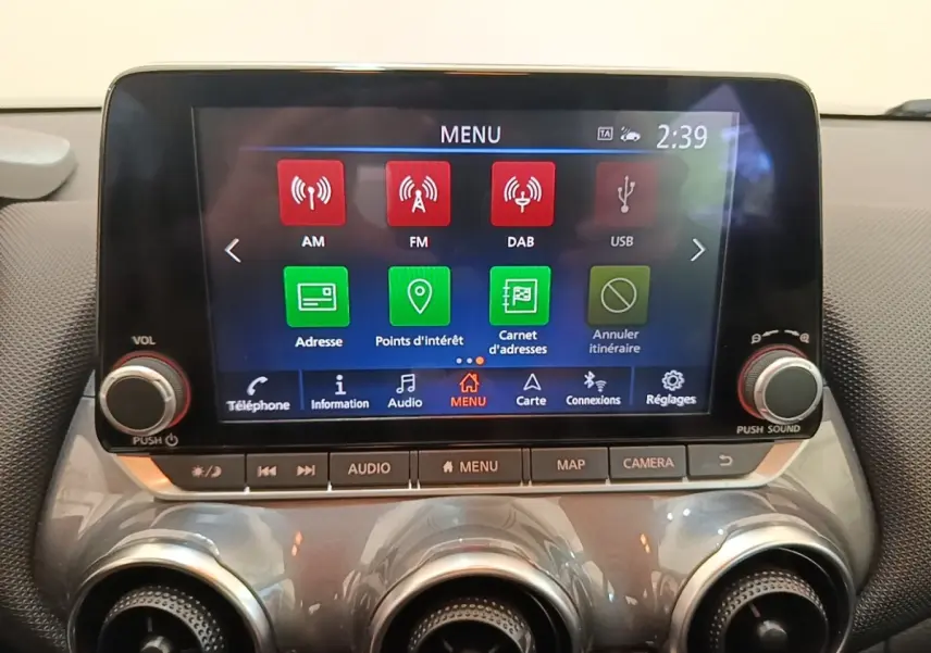 Écran tactile central 8 pouces du Nissan Juke gris clair 2023, avec commandes audio et navigation visibles.