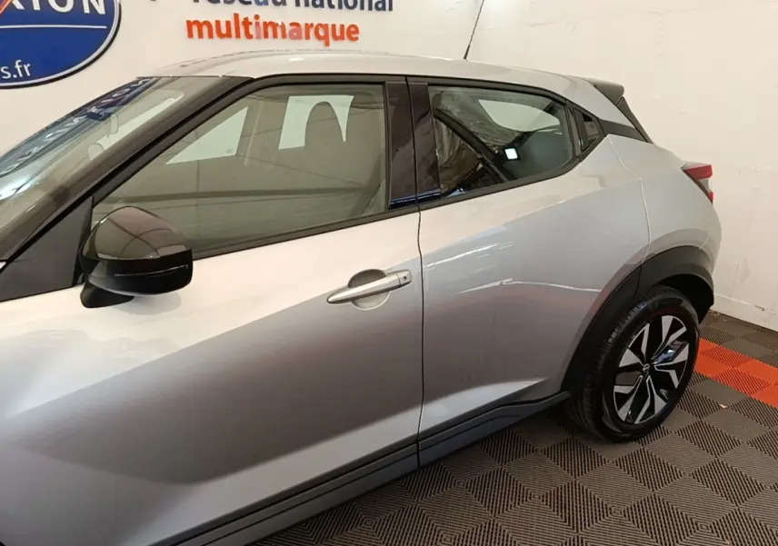 Vue côté droit du Nissan Juke gris clair 2023, mettant en valeur la ligne de caisse et les jantes noires à motifs.