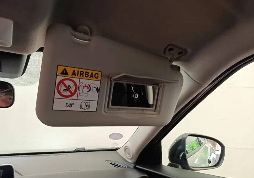 Vue intérieure côté passager du pare-soleil gris clair avec miroir et avertissement airbag du Nissan Juke 2023.