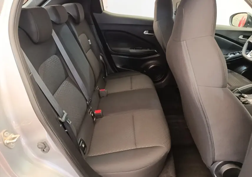 Vue intérieure côté gauche montrant la banquette arrière noire et les sièges avant du Nissan Juke gris clair 2023.