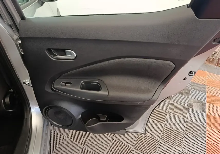Vue intérieure de la porte arrière gauche gris clair du Nissan Juke 2023 avec haut-parleur et poignée intégrée.