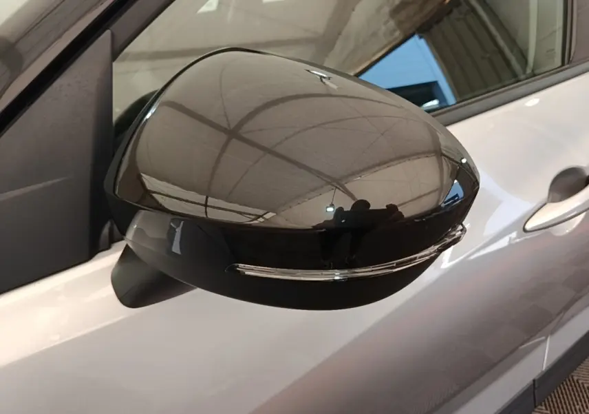 Rétroviseur noir brillant côté conducteur du Nissan Juke gris clair 2023, avec clignotant intégré visible.