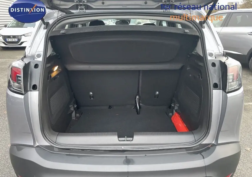 Coffre ouvert vu de l'arrière d'un Opel Crossland gris minéral métal, montrant l'espace de chargement vide.