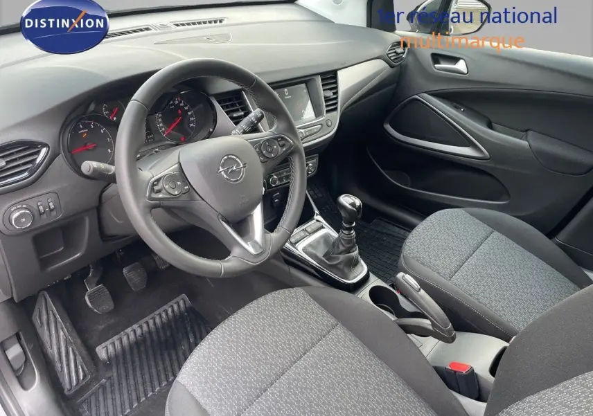Vue intérieure côté conducteur de l'Opel Crossland 2022 avec tableau de bord noir et sièges tissu gris.