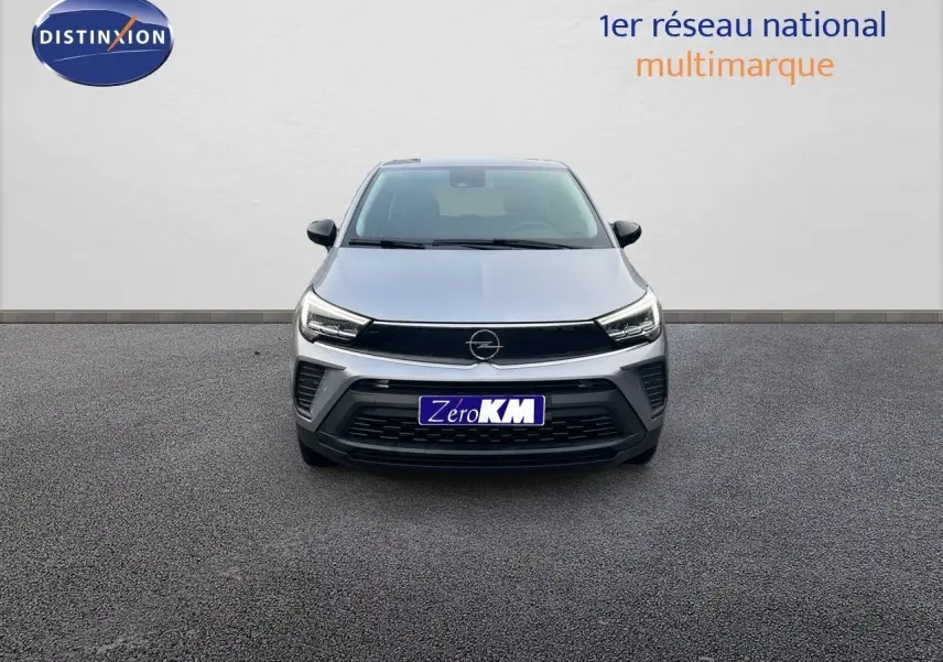 Vue frontale d'un Opel Crossland gris minéral métal avec calandre noire et phares LED allumés sur fond neutre.