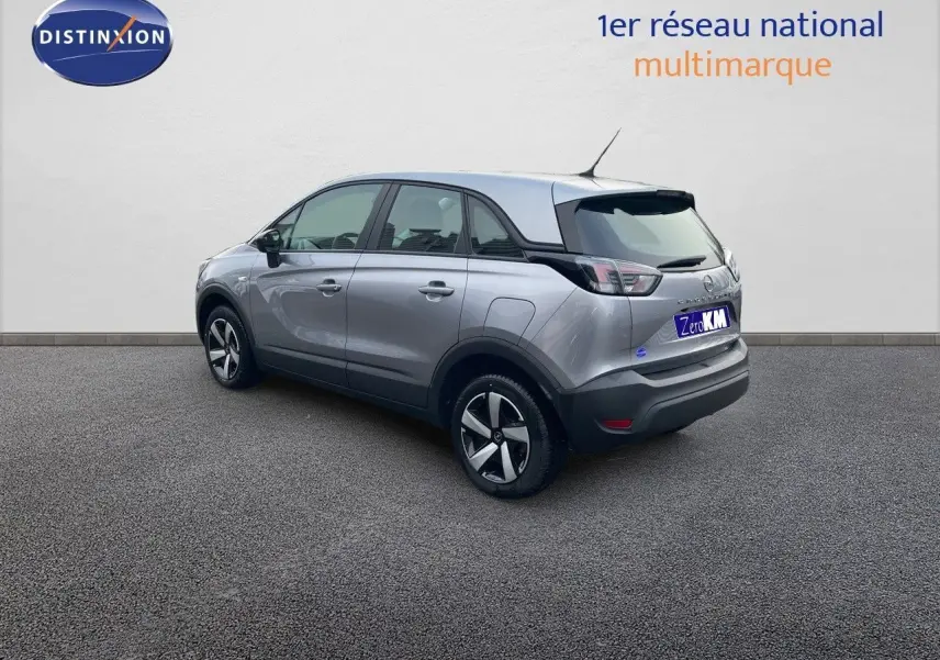 Opel Crossland gris minéral métal vu en 3/4 arrière côté gauche, avec jantes alliage et toit noir contrasté.