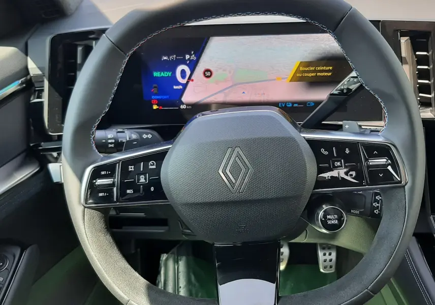 Vue rapprochée du volant multifonction noir et gris du Renault Espace VI 2025 avec tableau de bord numérique affichant la navigation.