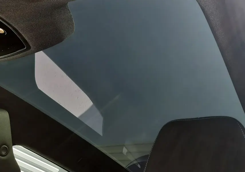Toit panoramique en verre vu de l'intérieur arrière d'un Renault Espace VI gris schiste avec appui-tête noir brodé bleu.
