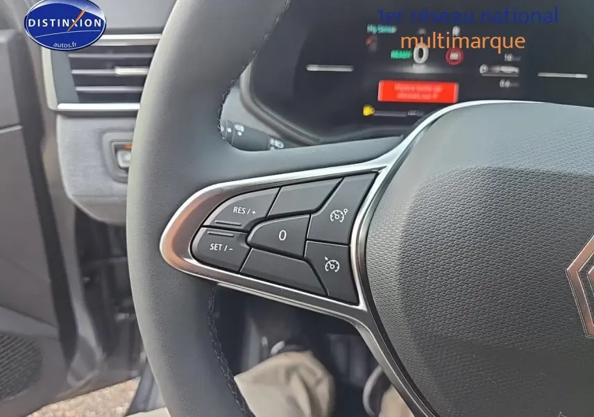 Gros plan sur le volant multifonction de la Renault Clio V gris schiste, avec commandes de régulateur de vitesse visibles.