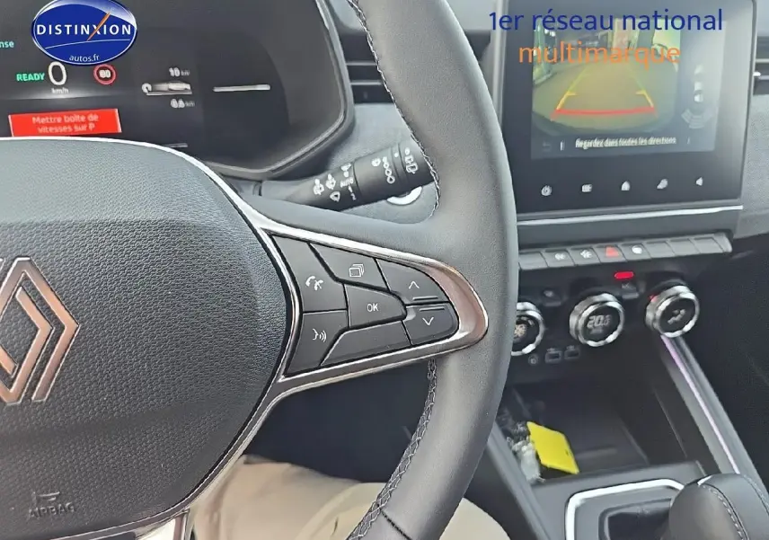 Vue intérieure centrée sur le volant multifonction et la console centrale d'une Renault Clio V gris schiste 2025