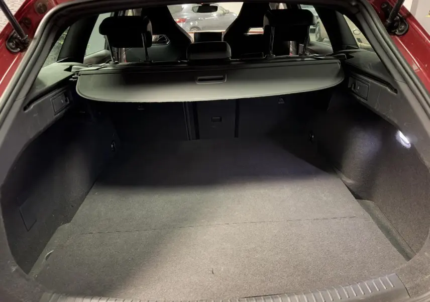 Coffre ouvert d'une CUPRA Leon Sportstourer rouge, vue arrière montrant l'espace de chargement avec cache-bagages noir.
