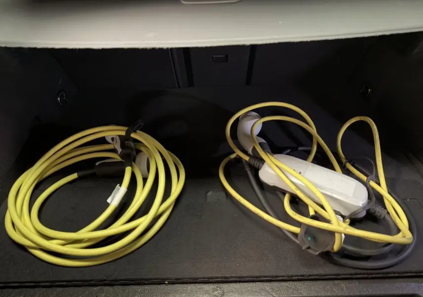 Gros plan sur le coffre d'une CUPRA Leon Sportstourer rouge avec câbles de recharge hybride jaune enroulés.