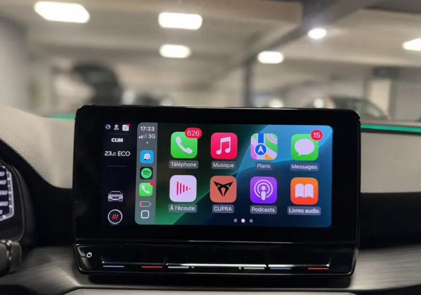 Écran tactile central affichant Apple CarPlay dans l'habitacle d'une CUPRA Leon Sportstourer rouge, vue de face.
