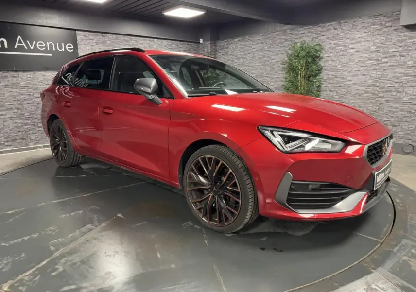 Vue 3/4 avant d'une CUPRA Leon Sportstourer rouge Désir avec jantes alliage noires et rétroviseurs gris.