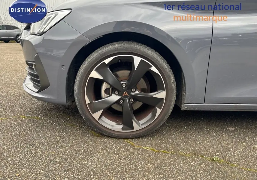 Gros plan sur la roue avant gauche et l'aile d'une CUPRA LEON ST gris Graphene metal avec jante bi-ton distinctive.