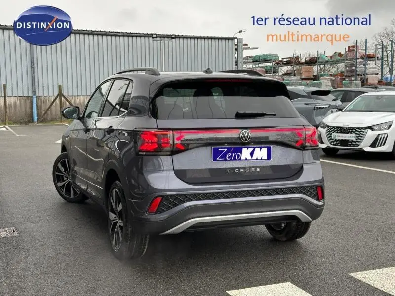 Vue 3/4 arrière droite d'un Volkswagen T-Cross 2025 gris Ascot avec feux arrière connectés et jantes alliage noires.