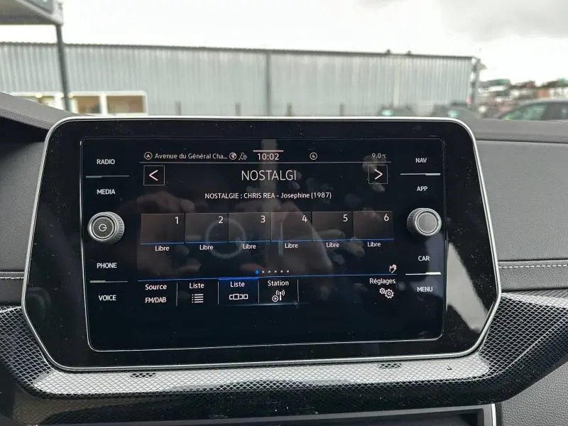 Écran tactile central du Volkswagen T-Cross 2025 affichant la radio NOSTALGIE, entouré d'une finition noire brillante.