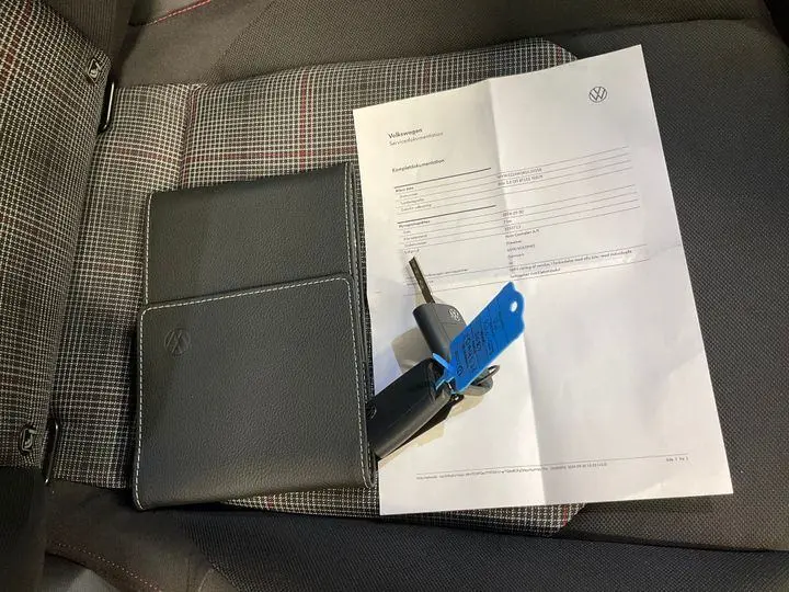 Vue rapprochée de la sellerie à motif tartan et tissu noir d’une Volkswagen Polo GTI 2024 avec clé et document posé dessus.