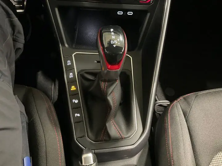 Vue rapprochée du levier de vitesse automatique noir et rouge de la Volkswagen Polo GTI 2024 avec coutures rouges sur les sièges sport.