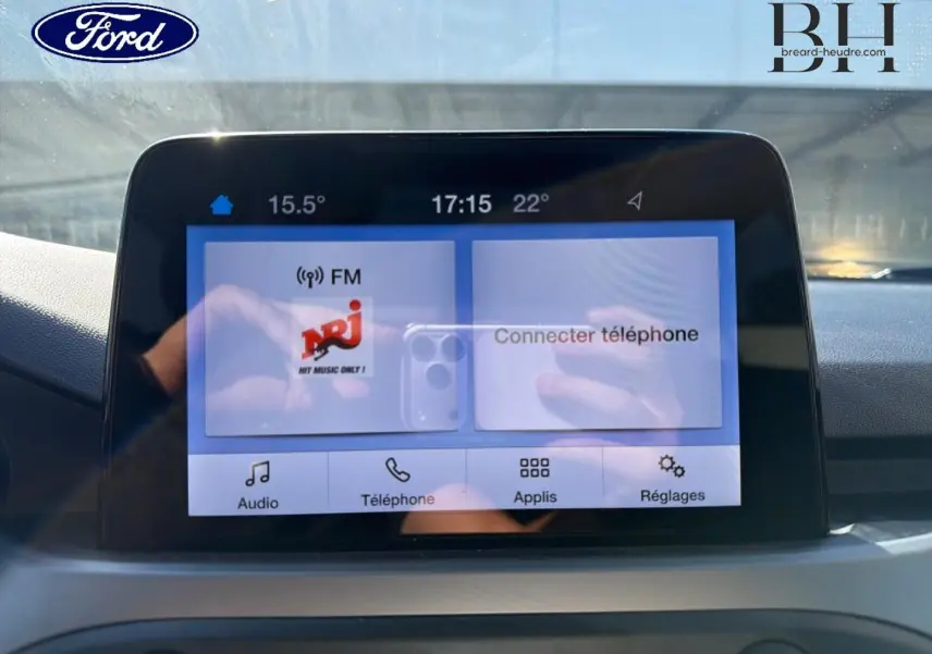 Écran tactile central de la Ford Focus 1.0 Flexifuel 2022 affichant la radio NRJ et les options de connexion téléphone.