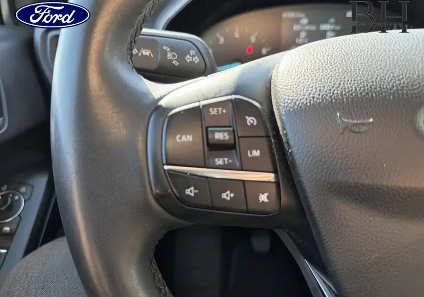 Gros plan sur le volant cuir multifonction noir de la Ford Focus 2022, avec commandes de régulateur et audio visibles.