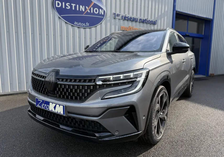 Vue 3/4 avant d'un Renault Espace gris schiste métal 2025 avec calandre noire et jantes bi-ton visibles.