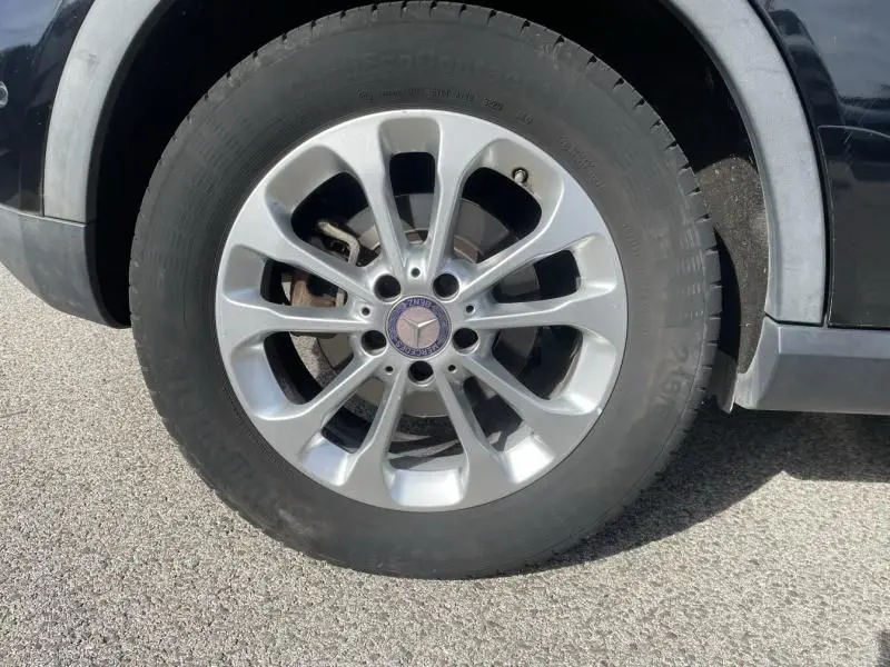 Gros plan sur la roue avant gauche noire d'un Mercedes GLA 200 D Sensation 2017 avec jante argentée étoilée.