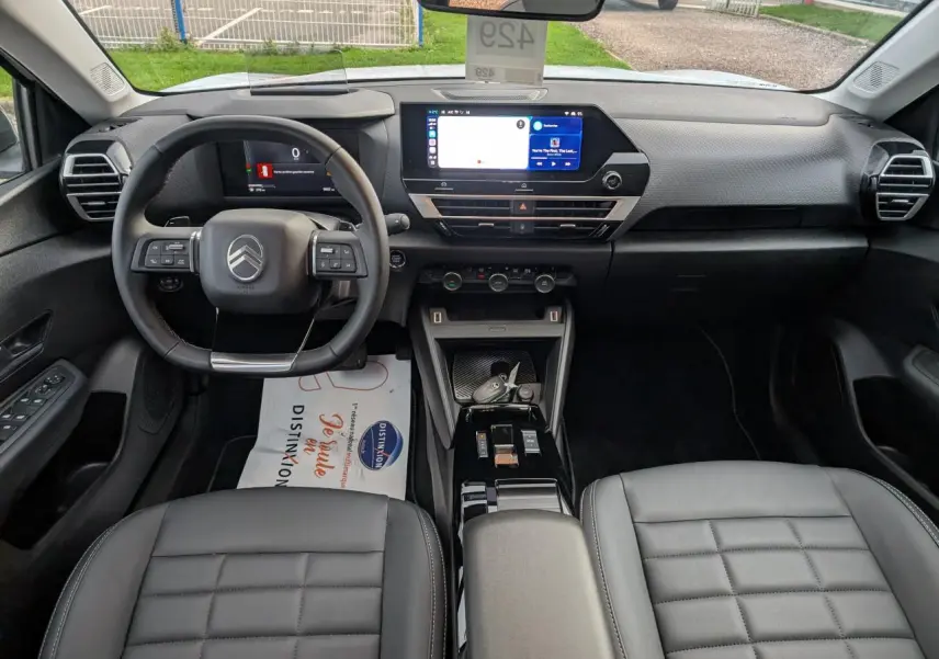 Intérieur noir de la Citroën C4 2025 vu de face, avec volant cuir, écran tactile et sièges matelassés.