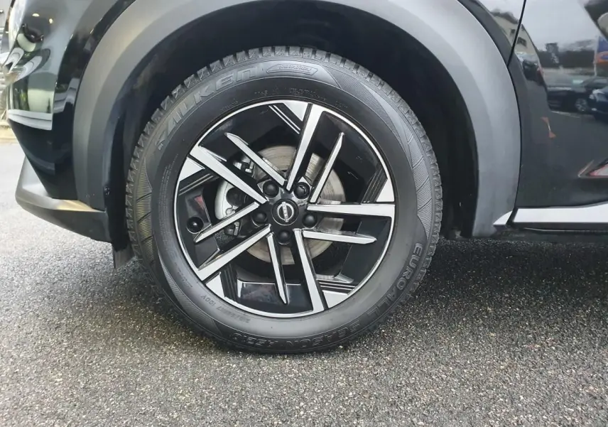 Gros plan sur la roue avant gauche noire du Nissan Juke 2025 avec jante alliage 17 pouces au design moderne.