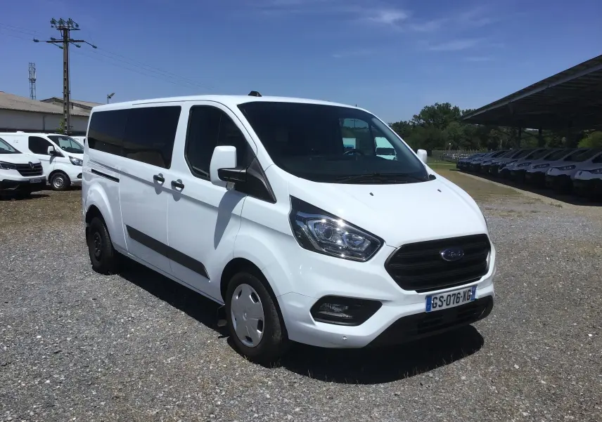 Ford Transit Custom Kombi blanc vu en 3/4 avant droit, avec vitres arrière teintées et jantes acier.