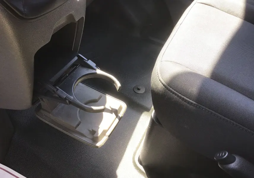 Gros plan intérieur sur le porte-gobelet déployé côté droit, avec siège tissu noir du Ford Transit Custom Kombi blanc 2023.