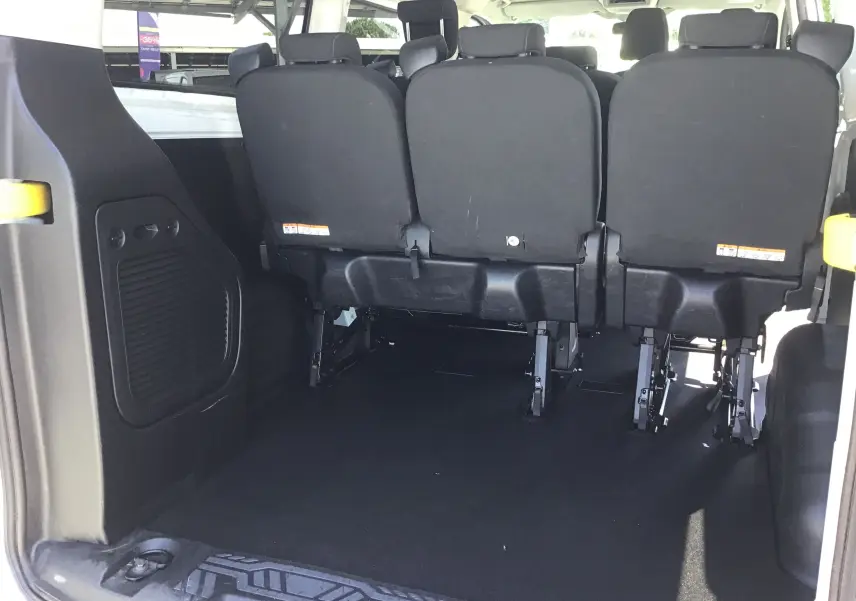 Vue arrière intérieure du Ford Transit Custom Kombi blanc 2023 montrant les sièges arrière noirs et l'espace de chargement vide.
