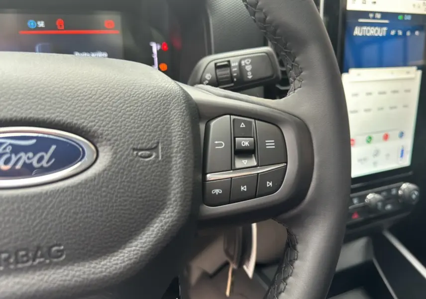 Gros plan sur le volant cuir multifonctions du Ford Ranger blanc glacier avec écran tactile et commandes au volant visibles.