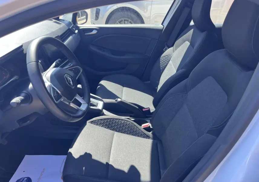 Vue intérieure côté conducteur de la Renault Clio blanc quartz, sièges tissu noir avec motifs surpiqués.