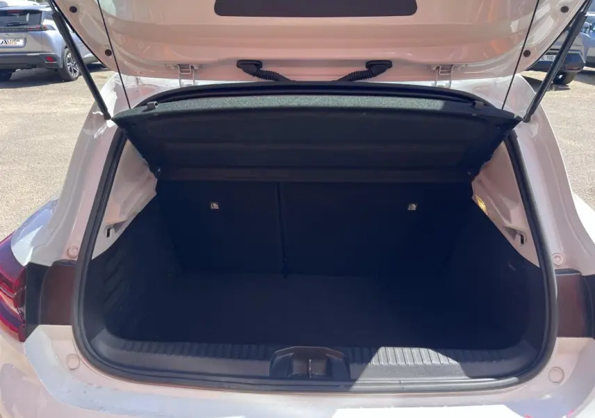 Coffre ouvert vu de l'arrière d'une Renault Clio blanc Quartz, espace de chargement vide et propre.
