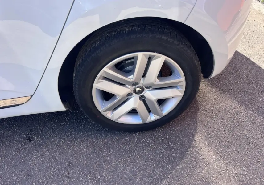 Gros plan sur la roue arrière droite d'une Renault Clio blanc Quartz avec jante alliage et partie de la carrosserie visible.
