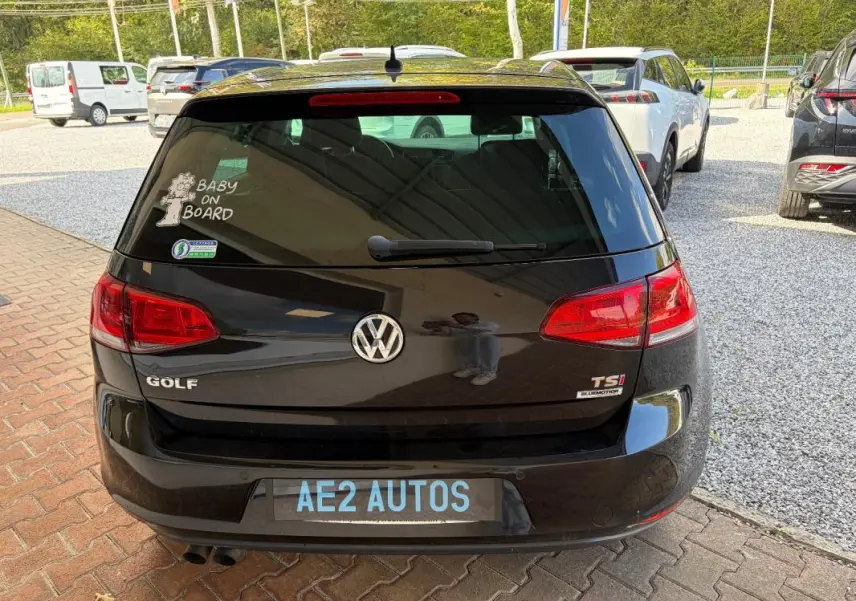 Vue arrière d’une Volkswagen Golf 7 noire de 2016 avec badge TSI et autocollant Baby on Board sur la vitre arrière.