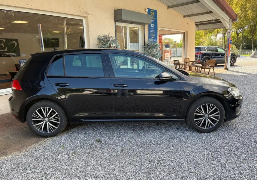 Volkswagen Golf 7 noire vue de profil côté gauche, avec jantes alliage et rétroviseurs électriques rabattables.