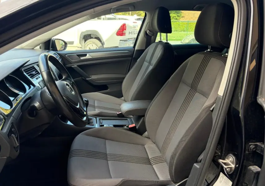 Intérieur de la Volkswagen Golf 7 noir, vue côté conducteur montrant sièges tissu et volant cuir multifonctions.