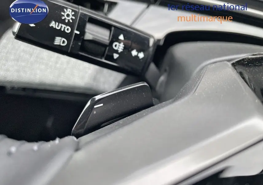 Gros plan sur la commande de feux et le levier de vitesses au volant d'un Peugeot 3008 noir perle métal 2025 hybride.