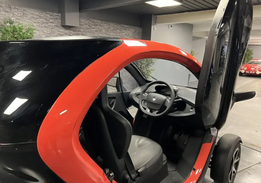 Vue intérieure côté droit de la Renault Twizy Intens 2019 orange avec porte élytre ouverte et siège noir visible.