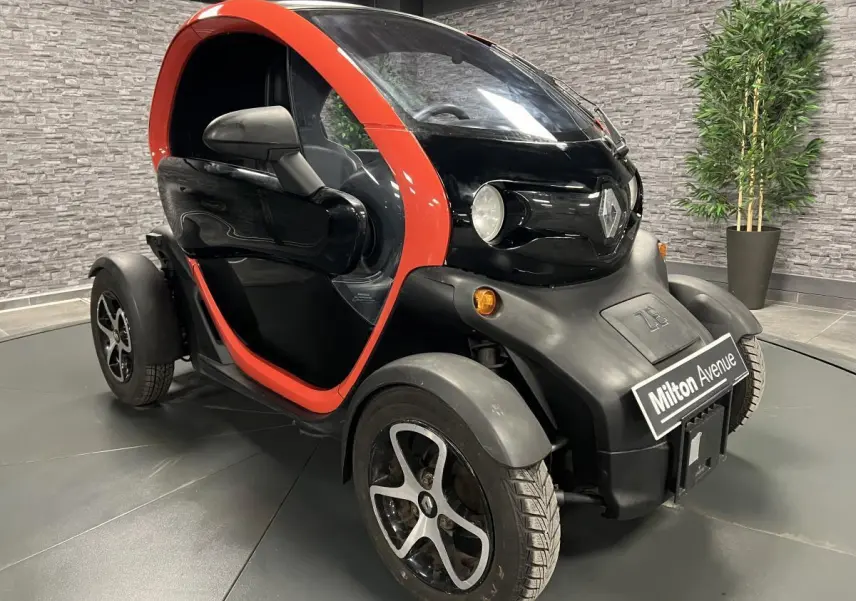 Vue 3/4 avant droite d'une Renault Twizy Intens 2019 orange avec portes élytre et jantes noires.