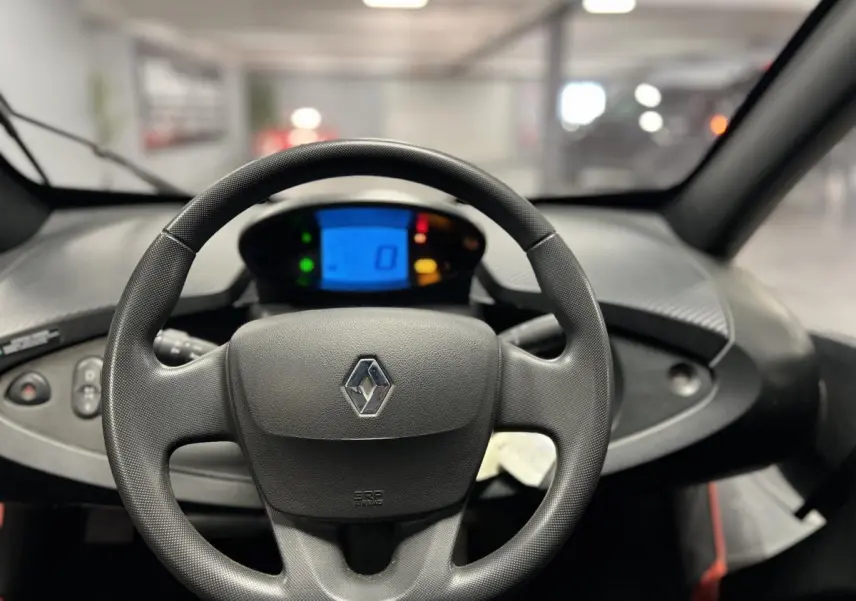 Vue intérieure centrée sur le volant noir de la Renault Twizy Intens 2019 avec tableau de bord digital bleu.