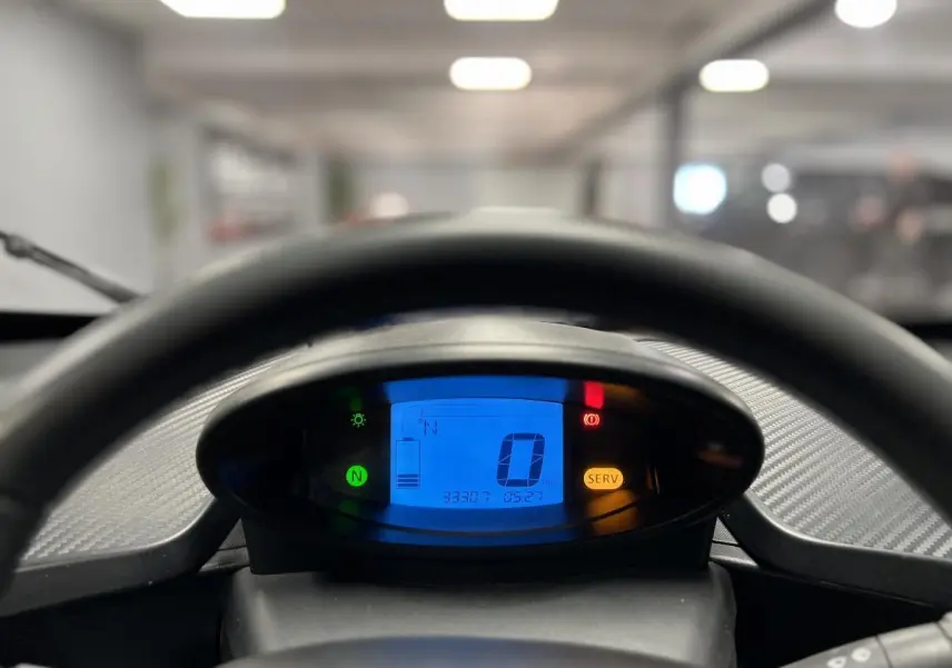 Vue rapprochée du tableau de bord numérique bleu de la Renault Twizy Intens orange, affichant vitesse et niveau batterie.