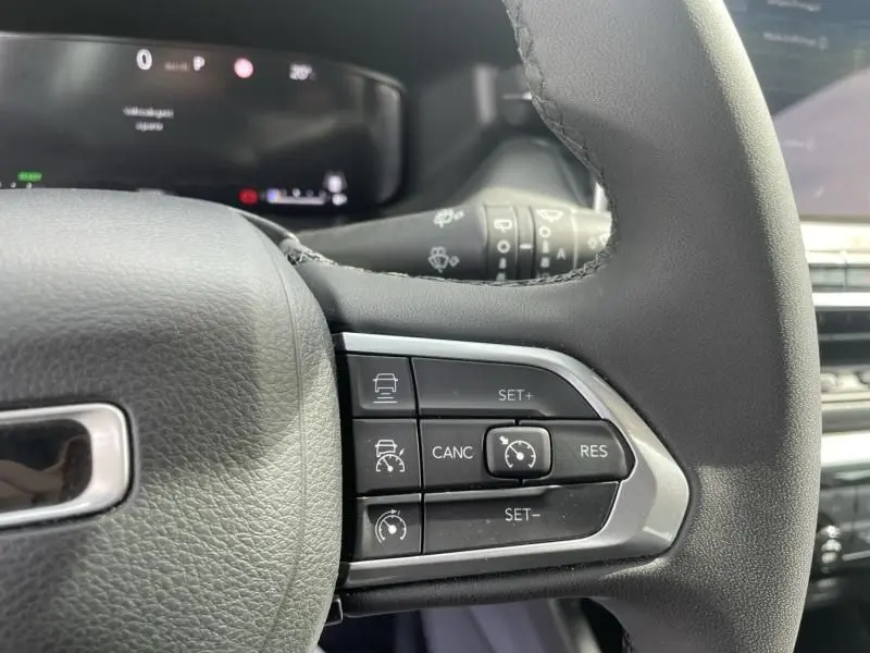 Gros plan sur les commandes de régulateur de vitesse au volant noir du Jeep Compass blanc 2024 hybride essence.