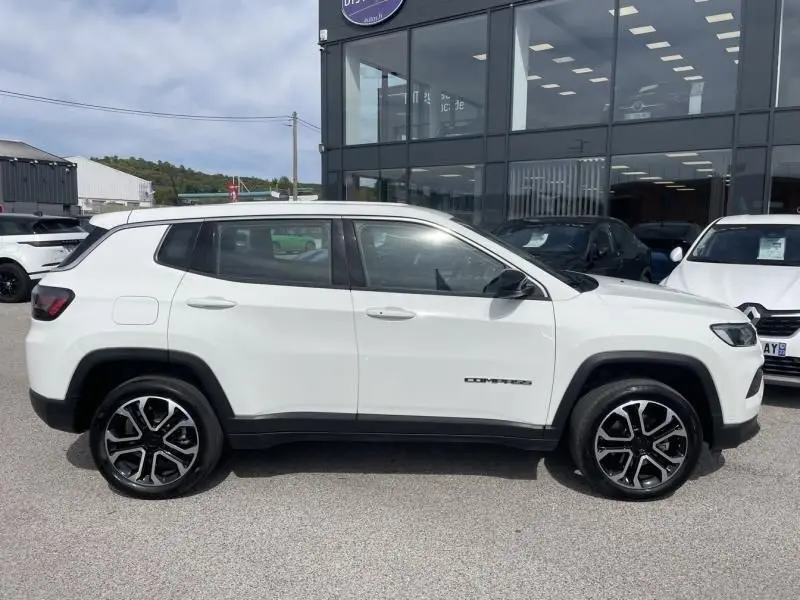Profil côté gauche du Jeep Compass blanc 2024, version hybride Altitude, avec jantes alliage noires et détails noirs contrastants.